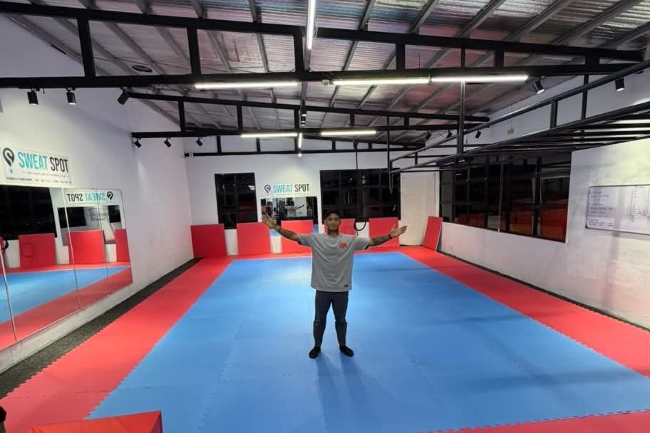 Red and blue puzzle-mat room with one person standing in the middle with arms outstretched